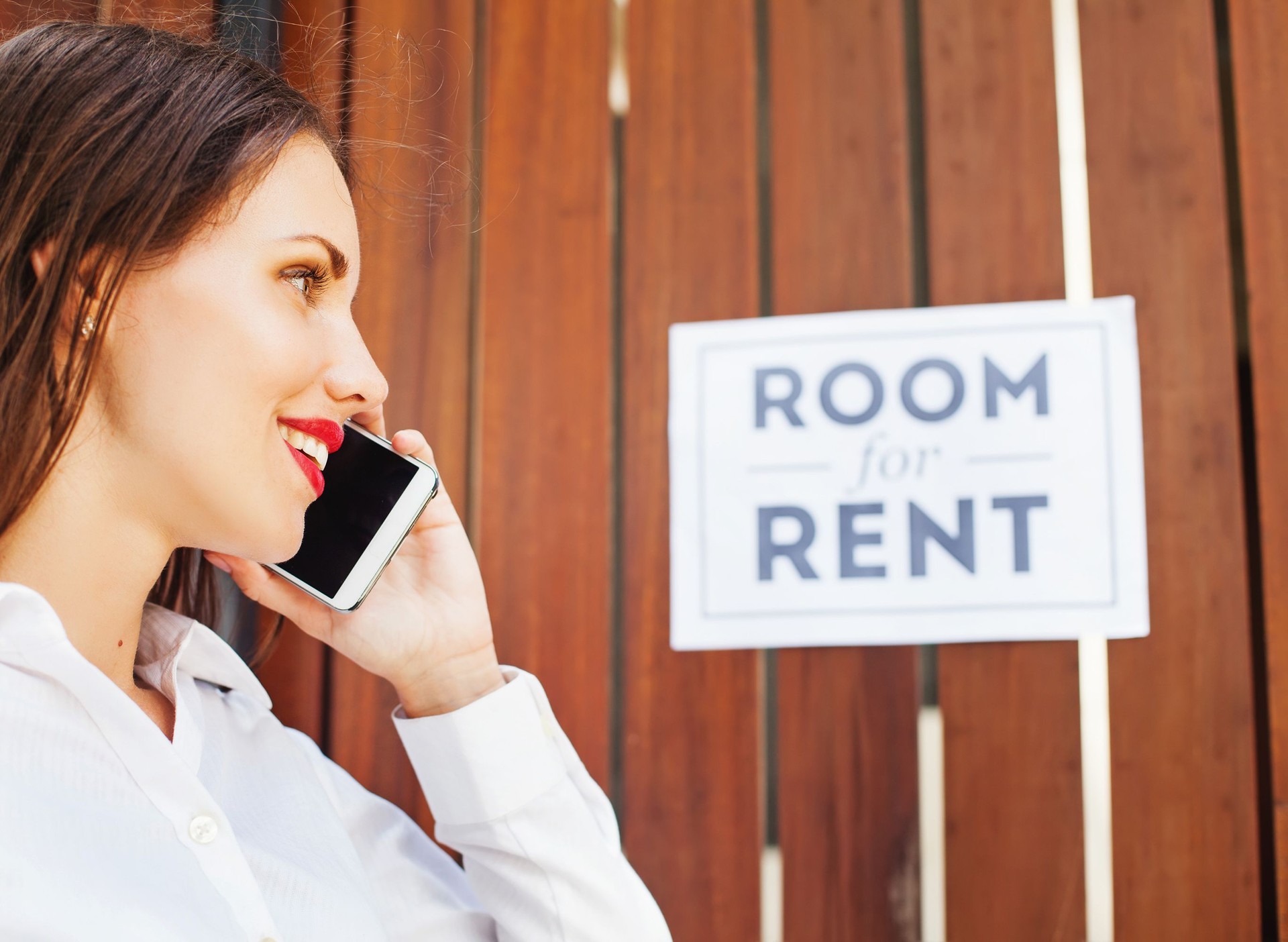 woman calling in front of "Room for rent" sign