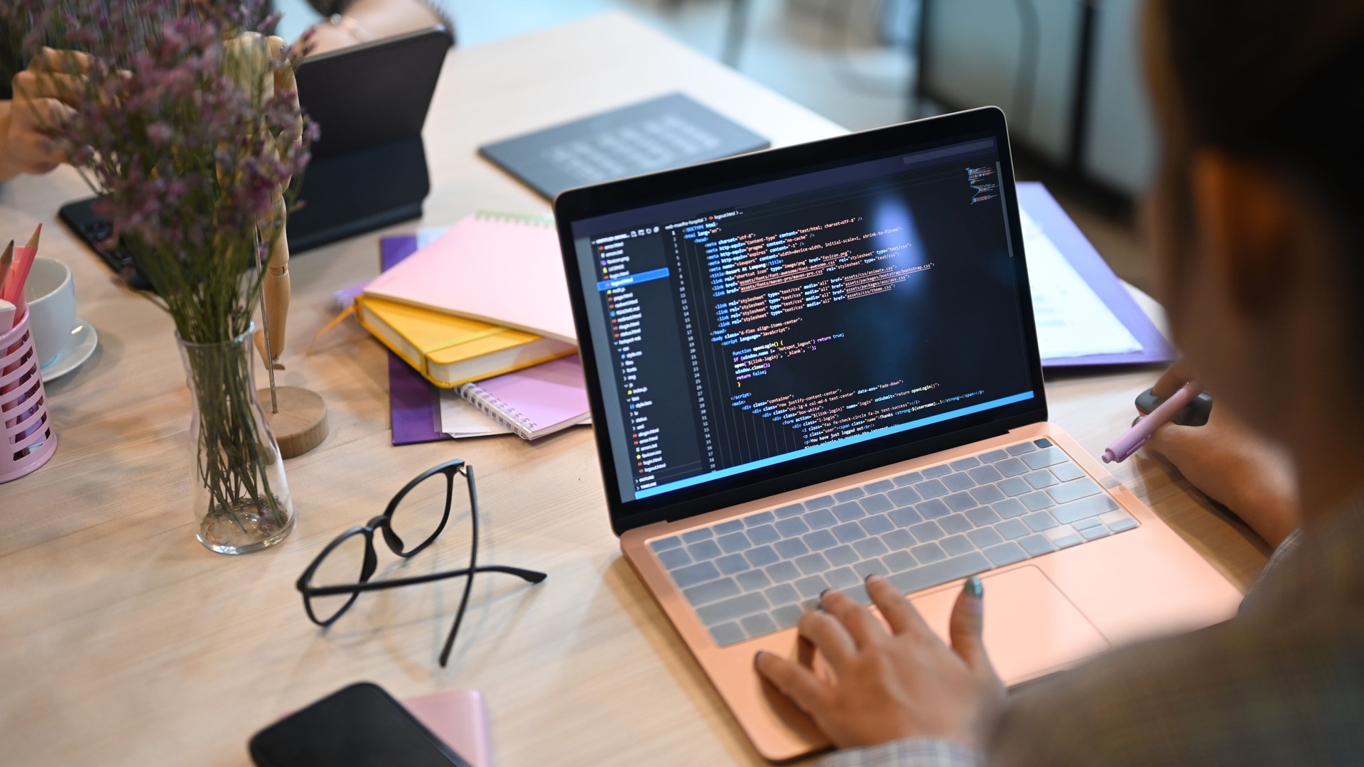 Over shoulder view of software developers programming on desktop computer in startup office.